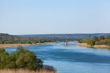 Obraz premium Dniester. View of the river from the railway bridge. The blue sky is reflected in the water.