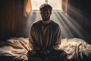 Emotive image of a standing male aged 20 praying in his bed