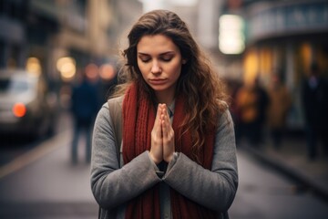 Emotive image of a standing female aged 20 praying in the street