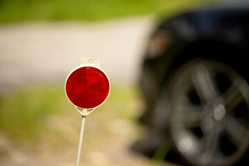 red STOP sign reflector and blurred image of a car in the background.