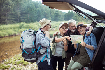 Group of senior friends using a map to navigate themselves in the forest while out hiking or camping
