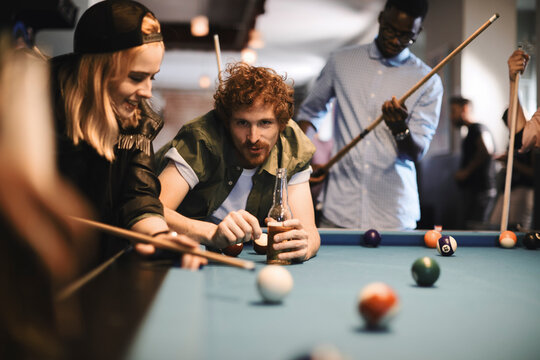 Young and diverse group of friends playing pool in a bar