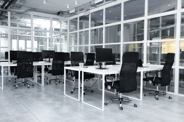 Fototapeta na wymiar Stylish interior of open plan office. Workspace with computers, tables and chairs