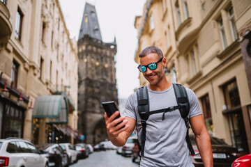 Fototapeta na wymiar Man looking at his phone and smiling while walking on the city street. Urban scene .