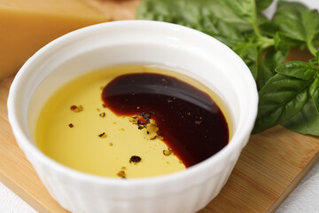 Bowl of organic balsamic vinegar with oil, spices and basil on table, closeup