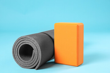 Exercise mat and yoga block on light blue background