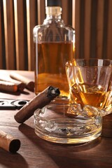 Obraz na płótnie Canvas Cigars, ashtray and whiskey on wooden table