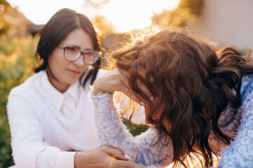 Concerned aged mother and adult daughter sitting on the sofa having a serious conversation, young woman talking to worried elderly mother, listening to her problems or concerns, helping cope with depr