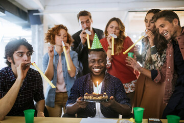 Young and diverse group of people celebrating a surprise birthday party in the office of a startup...