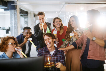 Young and diverse group of people celebrating a surprise birthday party in the office of a startup company
