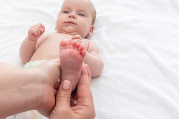 Newborn's feet under mother's soothing hands. Concept of motherly love and nurture