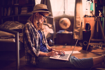 Young Caucasian woman using a laptop in a bedroom at home