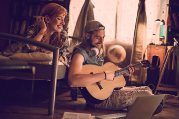 Obraz na płótnie Canvas Young couple playing the guitar and singing together in the bedroom at home