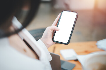 Cell phone Mockup image blank white screen, woman hand holding texting using mobile on desk at coffee shop, background empty space for advertise text.