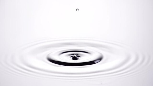 A single drop of water falling into a pool of water in slow motion.
