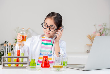 Asian little girl working with test tube science experiment in white classroom
