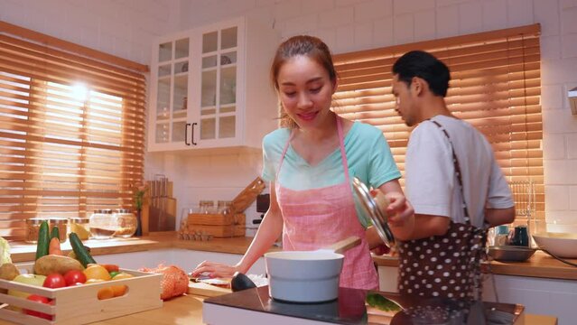 Asian young new marriage couple spend time together in kitchen at home.