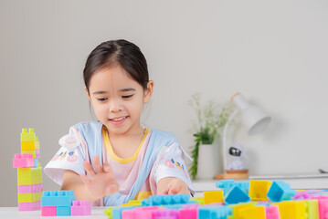 little girl is happy Playing colorful block puzzles. in the white room