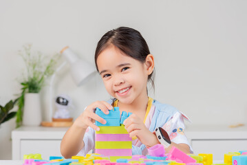 little girl is happy Playing colorful block puzzles. in the white room