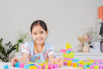 little girl is happy Playing colorful block puzzles. in the white room