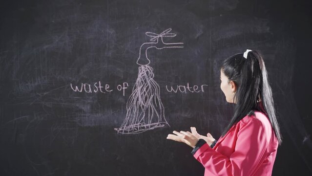 Woman writing water waste on blackboard looks at camera with frustration.
