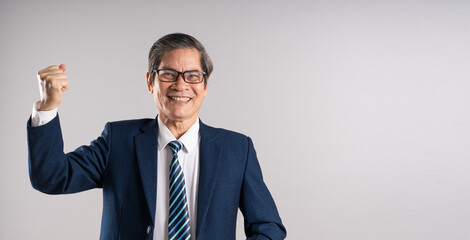 Portrait of an elderly Asian businessman, posing on a blue background
