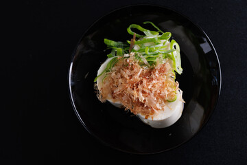 Japanese tofu Japanese appetizer soft cold tofu with sauce ginger and green onion topping isolated in black background