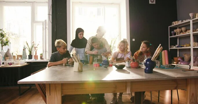 Teacher teaches students to work with pottery equipment