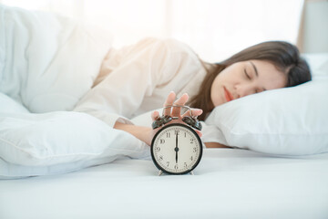 Young woman at home in morning, focus on alarm clock, alarm clock wake up woman in the room