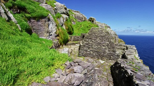 Beautiful houses established in the ancient times with detailed rock designs nearby the grass on the small hill in Skellig Michael, Ireland during a calm morning 