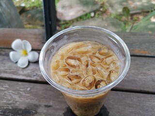 Iced coffee and flower on wood background