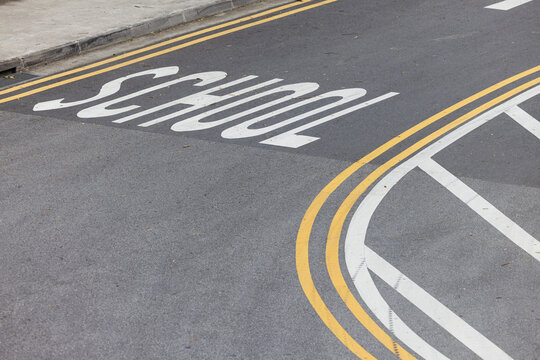 On the road near the school, the markings have been updated. Yellow and white lines on the asphalt indicate a turn, providing safety and clarity of traffic for drivers and pedestrians in this area.