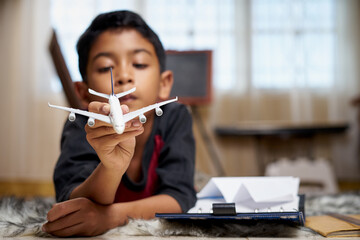 Schoolboy playing airplane toy while doing homework