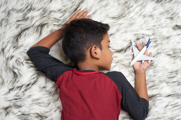 Young boy fall asleep holding airplane toy at home