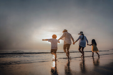 Happy Asian family consisting of father, mother, Son and daughter having fun playing on the beach.