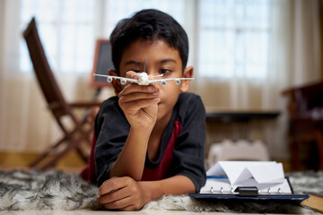 Schoolboy playing airplane toy while doing homework