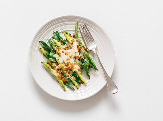 Grilled green string beans with mozzarella and lemon bread crumbs on a light background, top view