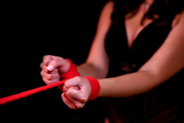 Close-up of female hands tied with a red rope. Black isolated background. Sex toys, Sex shop. Girl in sexy lingerie