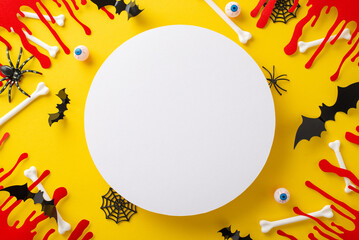 Artistic Halloween idea. Top view shot of themed embellishments, chilling blood streaks, bones, eyeballs, creepy crawlies, ghostly arachnids, web, bats on yellow backdrop, space for text insertion