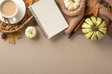 Warmth of autumn rustic vibe. Overhead shot featuring planner, pen, knitted scarf, fresh coffee, pattypans, cinnamon, maple leaves, pine cone on grey-beige backdrop. Empty area for text or promo