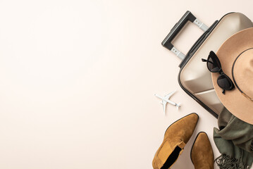 Sophisticated flying concept. Miniature plane model surrounded by classy items - felt hat, cat-eye shades, scarf, ankle boots, suitcase on neutral pastel background with empty space for advert