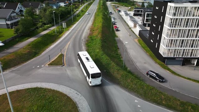 White bus drive through roundabout in Tromso neigborhood, aerial tracking