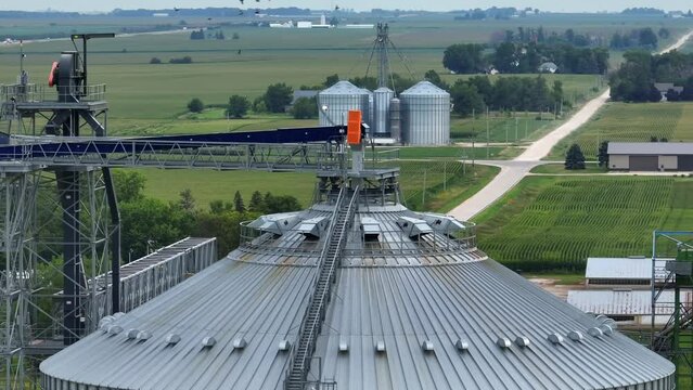 Top of a metal grain elevator bin. Aerial parallax orbit shot of grain, corn, and feed storage location in midwest USA.