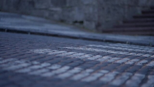 Close up of Car wheel driving through the crosswalk in historical European town with cube stone pavement during a blue hour at dusk. 4K, Sony FX3