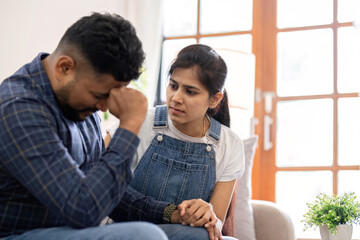 A young woman encourages and holds the hand of her worried husband. is having a hard time making some decisions.