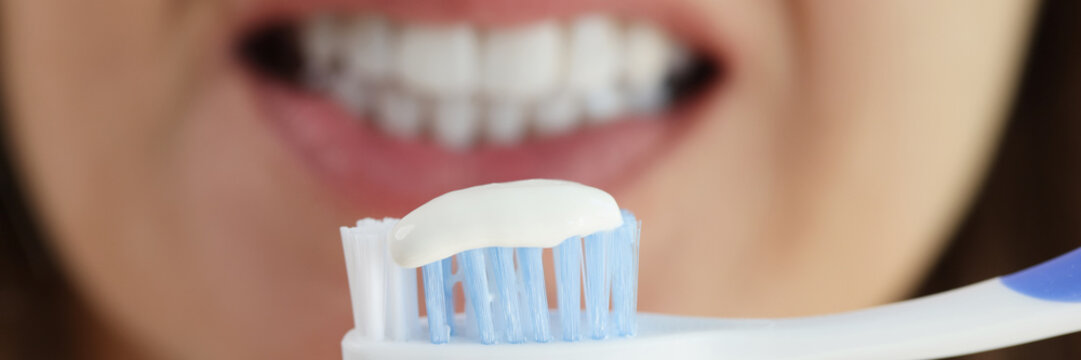 Woman holding tooth brush with snow white toothpaste, morning hygiene