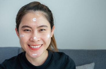 Asian woman smiling after she applying acne cream on her face for solving acne problem. Tretinoin...
