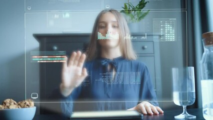 Young woman operating hologram starting from tablet on table in home office - Powered by Adobe