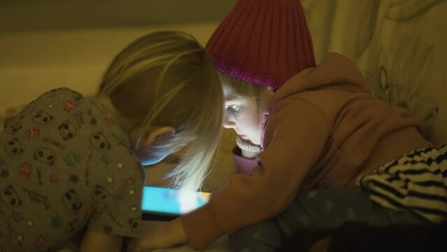 Two siblings a boy and a girl watch cartoons on the tablet. A close-up shot.