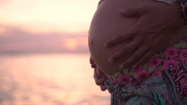 Expecting mother belly at the beach during sunset relaxing